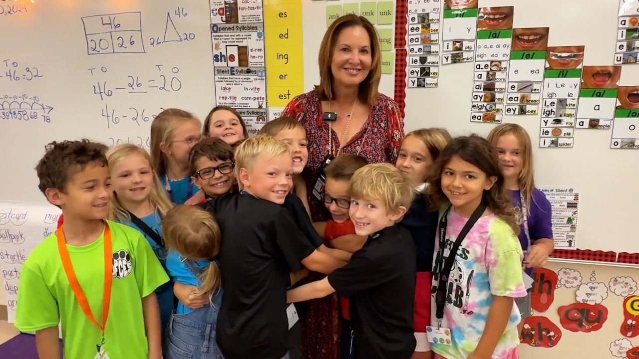  Sue Townsend, standing in the front of her classroom, hugging her students.